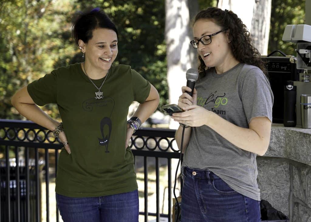 two women standing together, one talking into a microphone
