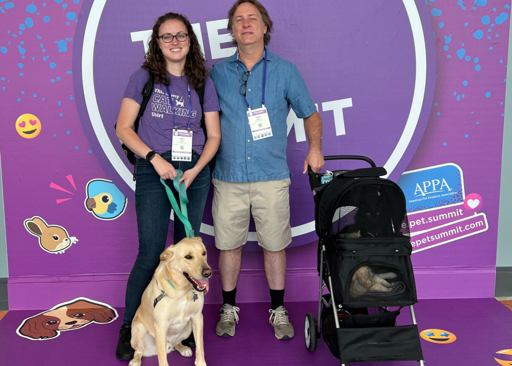 Woman and man with dog on leash and two cats in a stroller at Global Pet Expo
